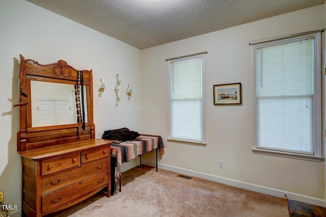 bedroom with light colored carpet and a textured ceiling