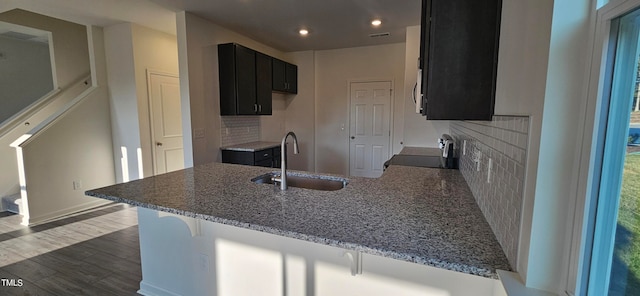 kitchen featuring sink, backsplash, a kitchen breakfast bar, kitchen peninsula, and stove