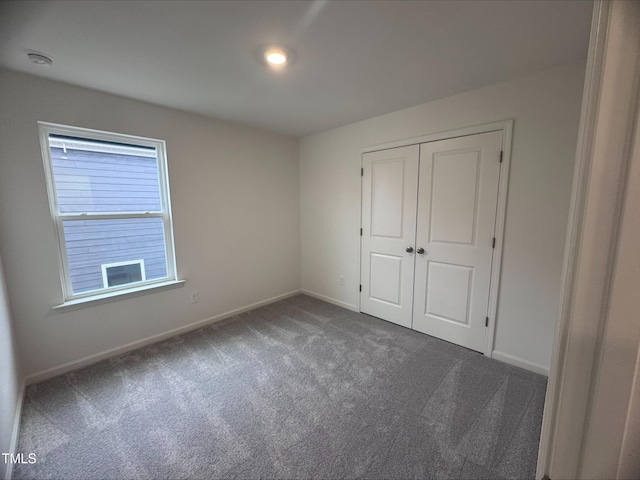 unfurnished bedroom with dark colored carpet and a closet