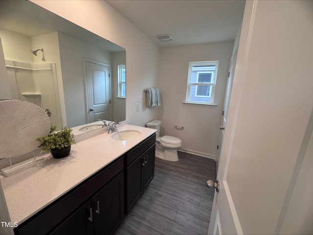 bathroom featuring hardwood / wood-style flooring, vanity, toilet, and walk in shower