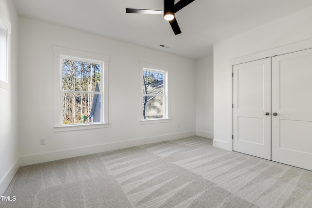 unfurnished bedroom with ceiling fan, a closet, and light colored carpet