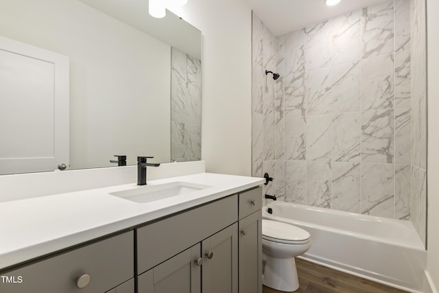 full bathroom featuring toilet, vanity, wood-type flooring, and tiled shower / bath