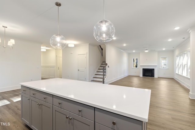 kitchen with gray cabinetry, decorative light fixtures, and light hardwood / wood-style flooring