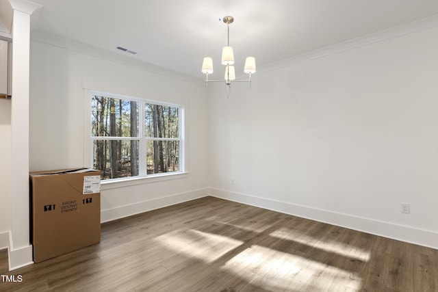 empty room with hardwood / wood-style floors, crown molding, and a notable chandelier