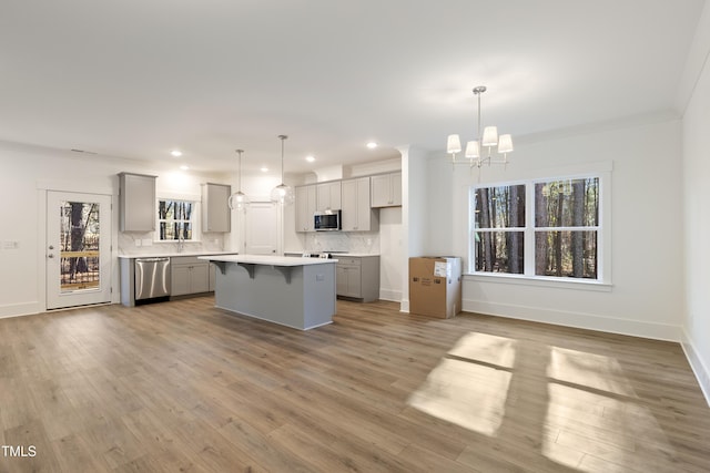 kitchen with decorative light fixtures, a center island, stainless steel appliances, and gray cabinetry