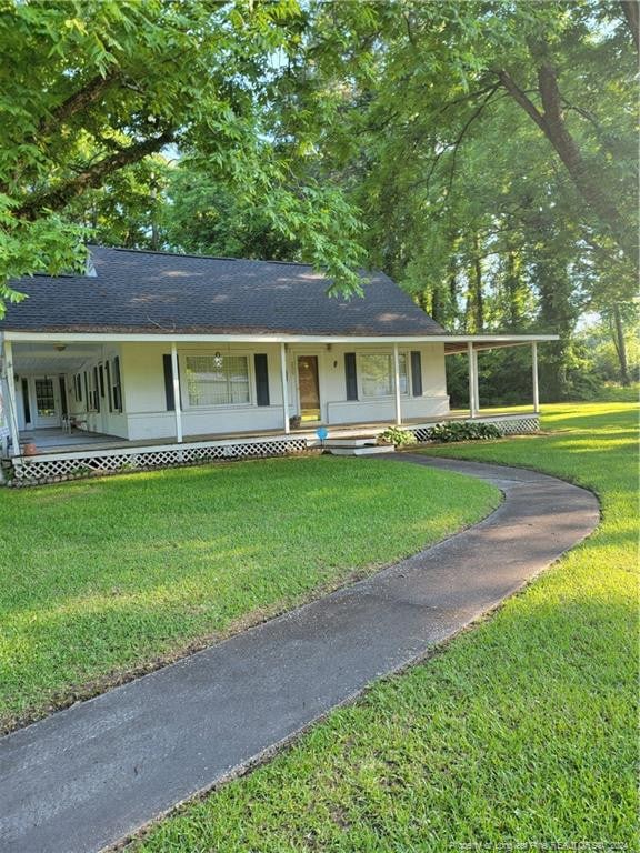 view of front of home featuring a porch, roof with shingles, and a front lawn