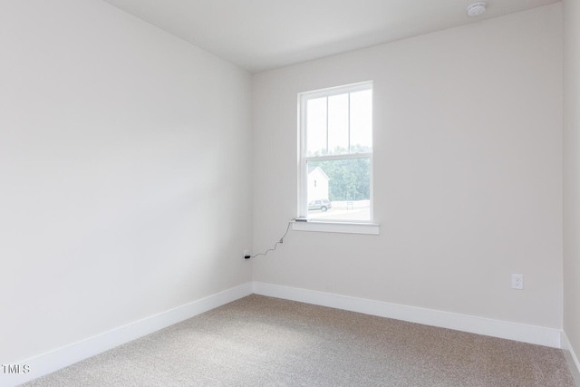 carpeted empty room with a smoke detector and baseboards