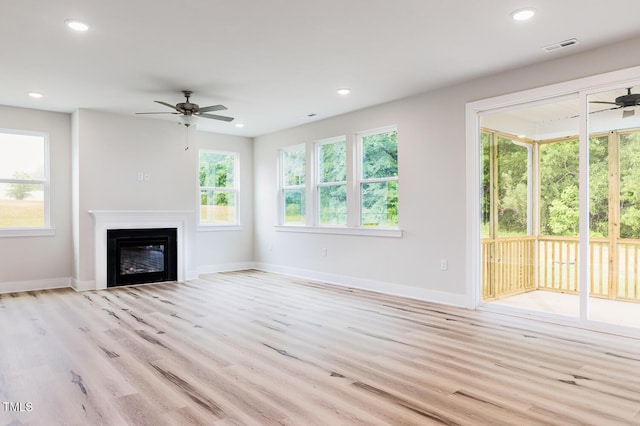 unfurnished living room with ceiling fan, light wood-type flooring, baseboards, a glass covered fireplace, and recessed lighting