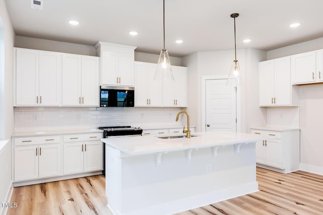 kitchen with a sink, light wood finished floors, light countertops, decorative backsplash, and recessed lighting