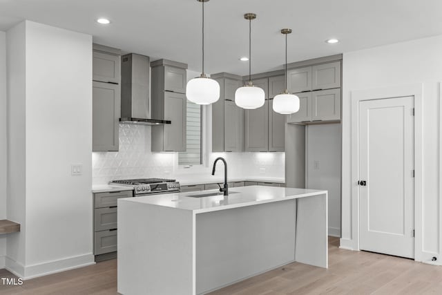 kitchen with gray cabinets, a sink, and wall chimney range hood