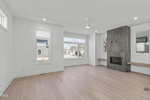 unfurnished living room with light wood finished floors, baseboards, visible vents, a fireplace, and recessed lighting