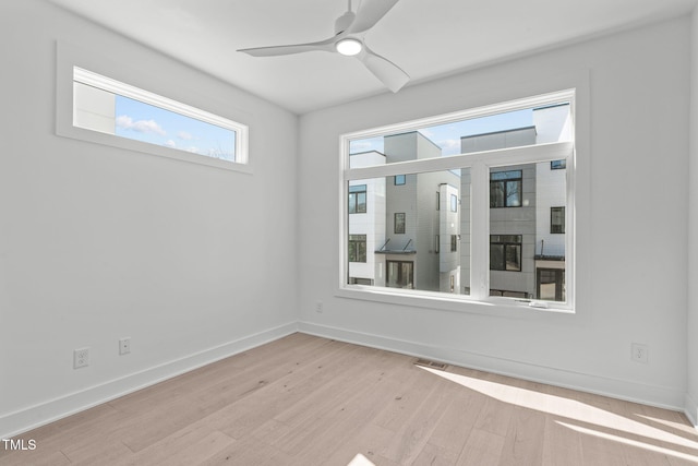 spare room featuring baseboards, ceiling fan, visible vents, and wood finished floors