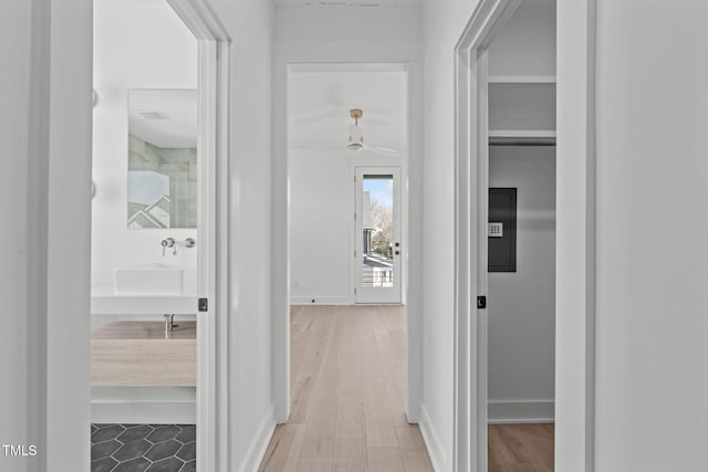 hallway with a sink, wood finished floors, and baseboards