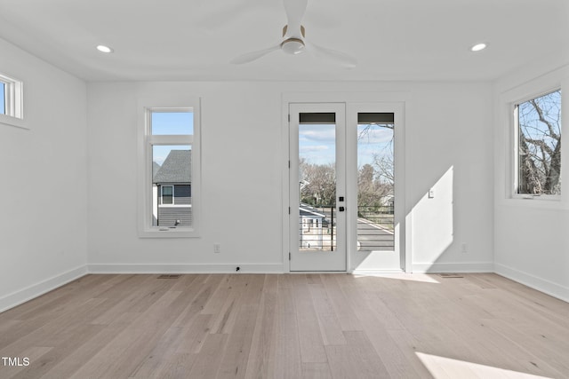 spare room with light wood-style flooring, a wealth of natural light, and baseboards