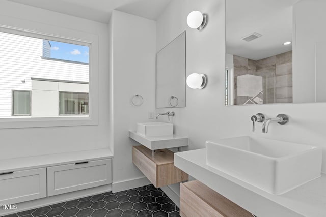 full bathroom with visible vents, vanity, tile patterned flooring, tiled shower, and baseboards