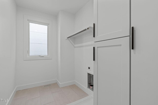 laundry area with laundry area, baseboards, electric dryer hookup, and light tile patterned flooring