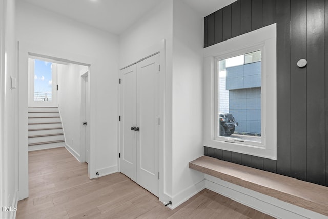 corridor with baseboards, stairway, and light wood finished floors