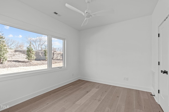 spare room featuring visible vents, a ceiling fan, light wood-style flooring, and baseboards