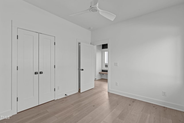 unfurnished bedroom featuring light wood-style floors, a closet, baseboards, and a ceiling fan