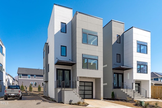 modern home featuring an attached garage, concrete driveway, and french doors