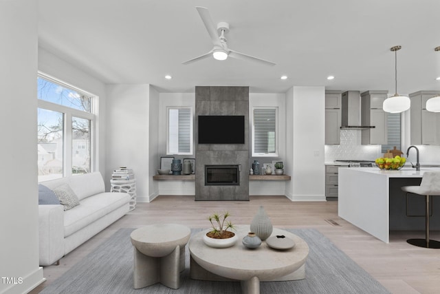 living room with light wood-style floors, a tile fireplace, baseboards, and recessed lighting