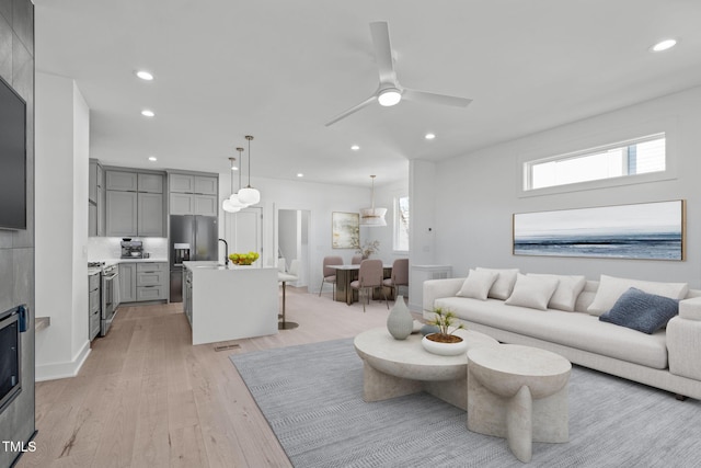 living room featuring light wood-style flooring, a ceiling fan, and recessed lighting