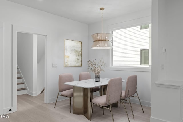 dining area featuring stairway, light wood-style flooring, and baseboards