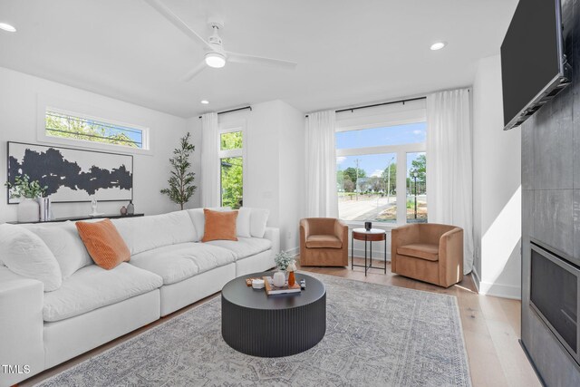 living room featuring recessed lighting, ceiling fan, baseboards, and light wood-type flooring