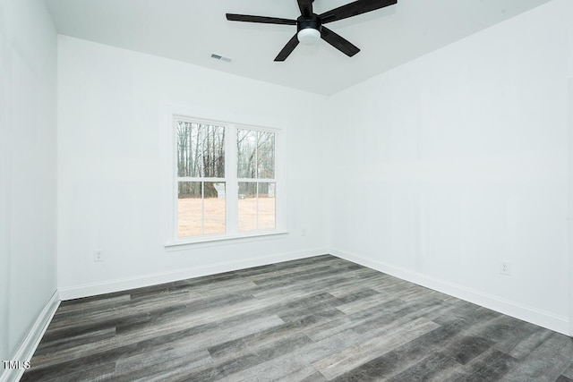 empty room with dark wood-style floors, baseboards, visible vents, and a ceiling fan