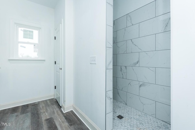 full bath featuring baseboards, a walk in shower, and wood finished floors