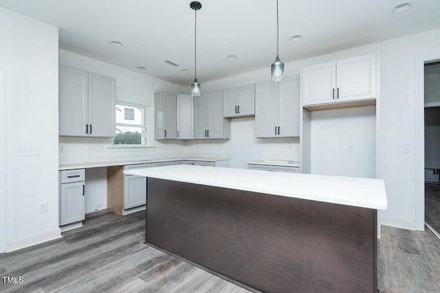 kitchen with light countertops, dark wood-style flooring, a kitchen island, and pendant lighting