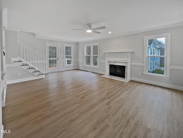 unfurnished living room with light hardwood / wood-style floors, ceiling fan, a premium fireplace, and ornamental molding