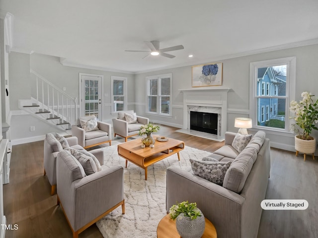 living room featuring a fireplace, ceiling fan, wood-type flooring, and crown molding