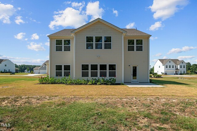 rear view of house featuring a patio, a garage, and a yard