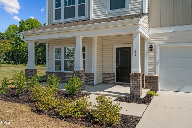 doorway to property with a garage and a porch