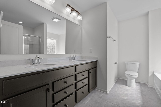 bathroom featuring a bath, tile patterned floors, toilet, and dual bowl vanity