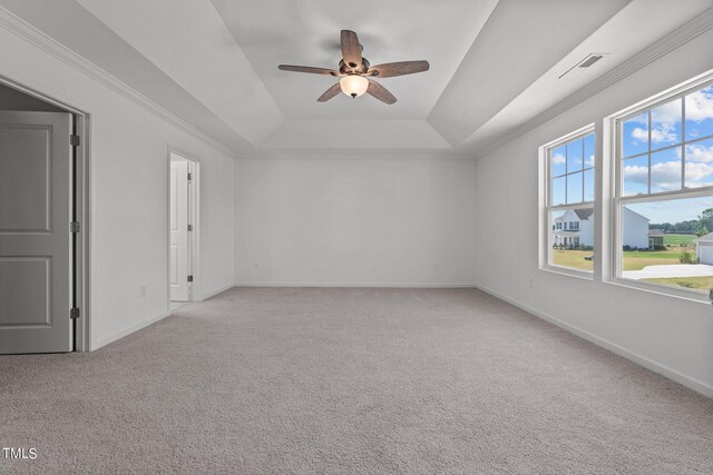 empty room featuring ceiling fan, light colored carpet, and a tray ceiling