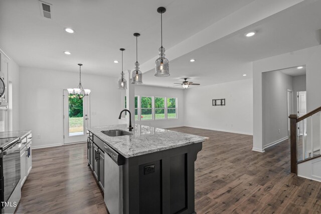 kitchen with ceiling fan with notable chandelier, dark hardwood / wood-style flooring, an island with sink, appliances with stainless steel finishes, and sink