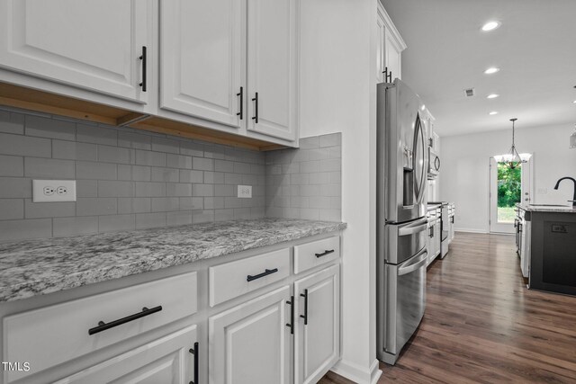 kitchen featuring tasteful backsplash, white cabinets, light stone counters, stainless steel refrigerator with ice dispenser, and dark wood-type flooring