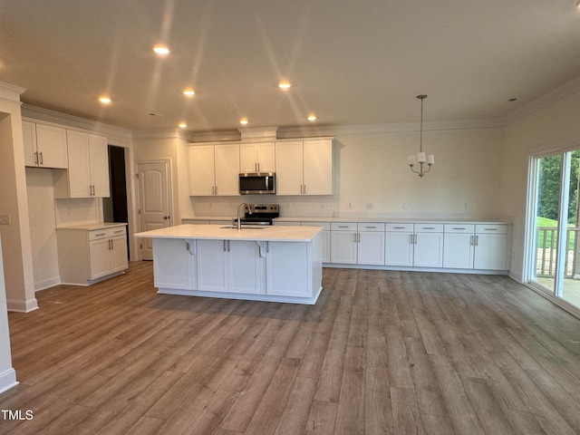 kitchen with hanging light fixtures, an island with sink, white cabinets, and appliances with stainless steel finishes