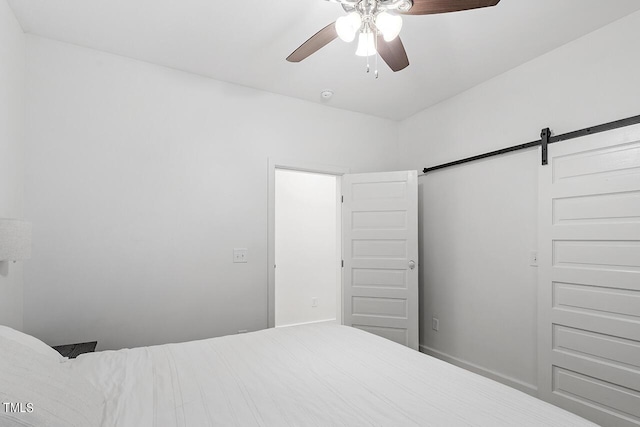 bedroom with ceiling fan and a barn door