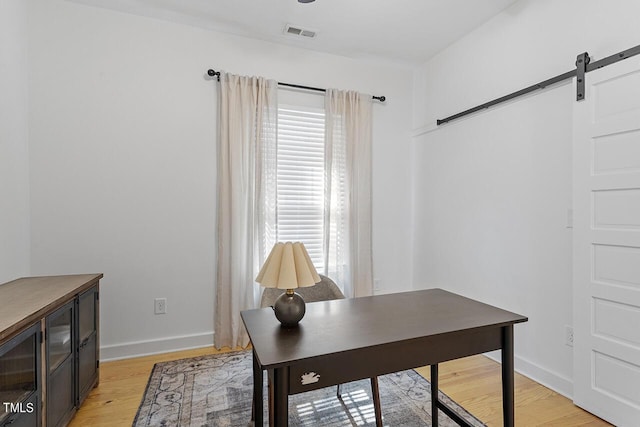 office area with a barn door and light hardwood / wood-style flooring