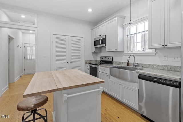 kitchen with sink, a center island, white cabinets, and appliances with stainless steel finishes