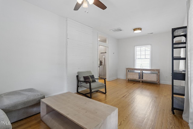 sitting room with ceiling fan and wood-type flooring