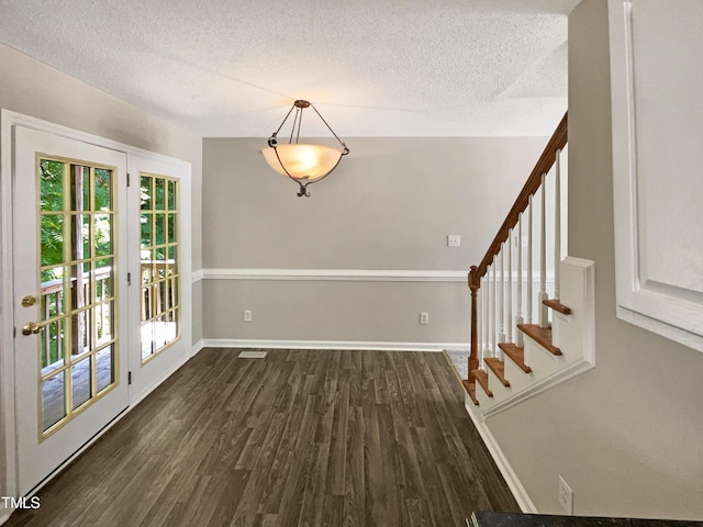 unfurnished dining area featuring a textured ceiling and dark wood-type flooring