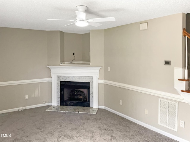 unfurnished living room featuring a fireplace, a textured ceiling, carpet floors, and ceiling fan