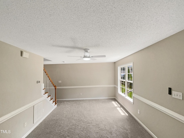 unfurnished room with a textured ceiling, carpet floors, and ceiling fan