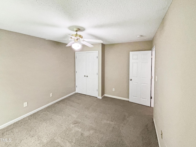 unfurnished bedroom with a textured ceiling, a closet, dark carpet, and ceiling fan