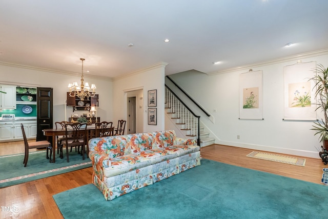 living room with crown molding, a chandelier, and light wood-type flooring