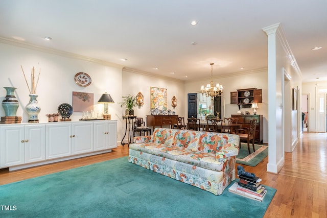 living room with light hardwood / wood-style floors, ornamental molding, and a notable chandelier